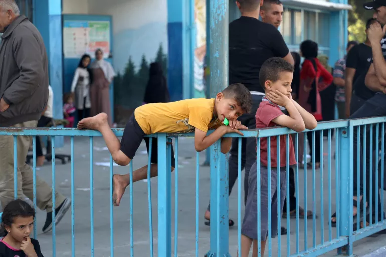 alestinian boy sleeping on metal fence looking at the horizon , war on Gaza forced dozens of families from Beit Hanoun city to evacuate and leave their houses running from heavy shelling escaping into UNRWA shelter.