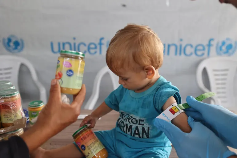 child being measured with MUAC tape for malnutrition