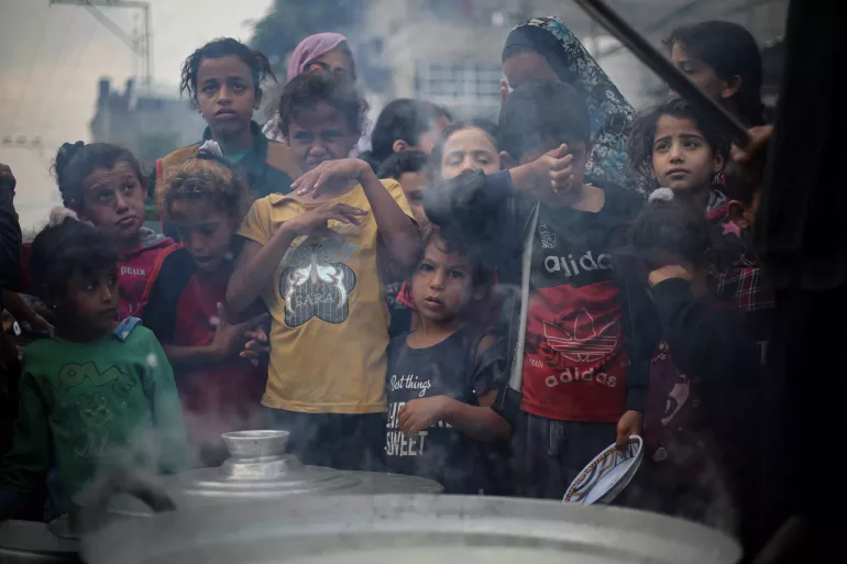 A group of children wait for the food prepared by a community initiative to feed displaced people in the streets of Khan Younis, southern the Gaza Strip.