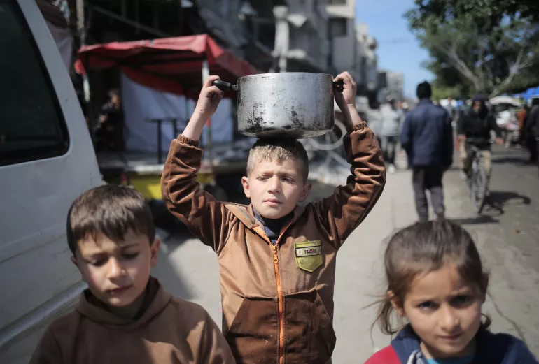 9-year-old Fadi walks the street while holding a pot of food on his head in Rafah, southern the Gaza Strip. 
