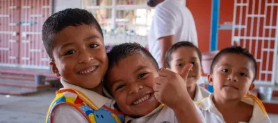 Cuatro ni&ntilde;os sonr&iacute;en y juegan juntos en el patio de su escuela.