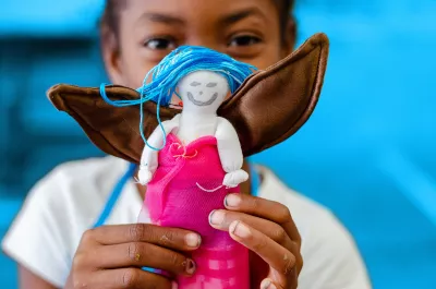 Ni&ntilde;a migrante sosteniendo una figura con alas