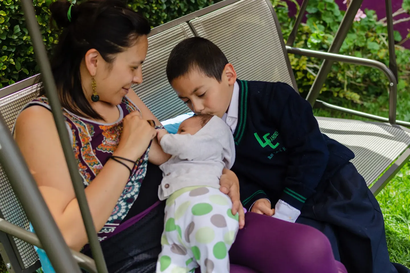Una familia de mam&aacute;, beb&eacute; e hijo. La madre est&aacute; dando pecho a su beb&eacute;