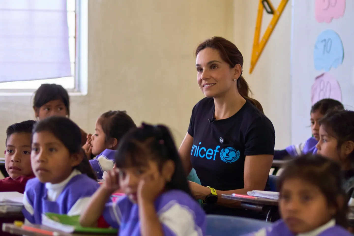 Tania Rinc&oacute;n sentada en un sal&oacute;n de clases junto a ni&ntilde;os y ni&ntilde;as en Chiapas