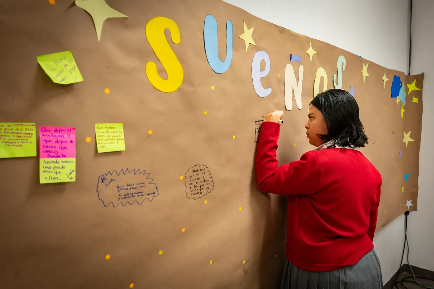 Una joven escribiendo su sue&ntilde;o en un mural