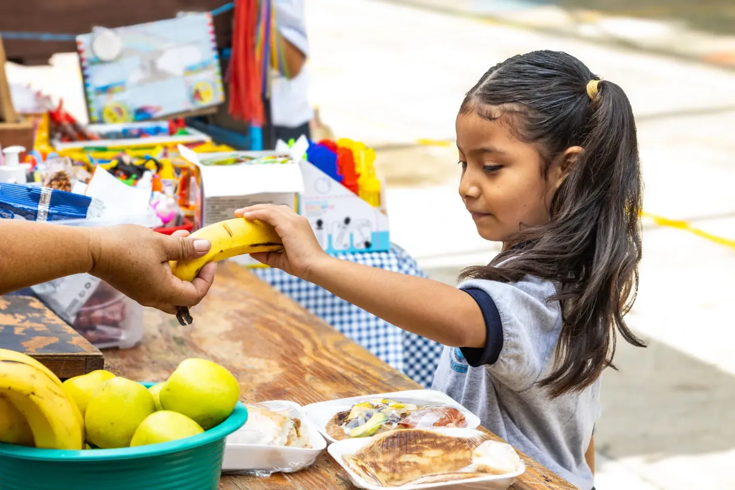 Ni&ntilde;a recibe una fruta en un comedor escolar donde se distribuyen alimentos frescos.