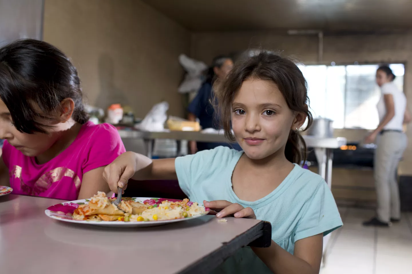: Una ni&ntilde;a disfruta una comida nutritiva en un comedor, ejemplo de alimentaci&oacute;n saludable para ni&ntilde;os.