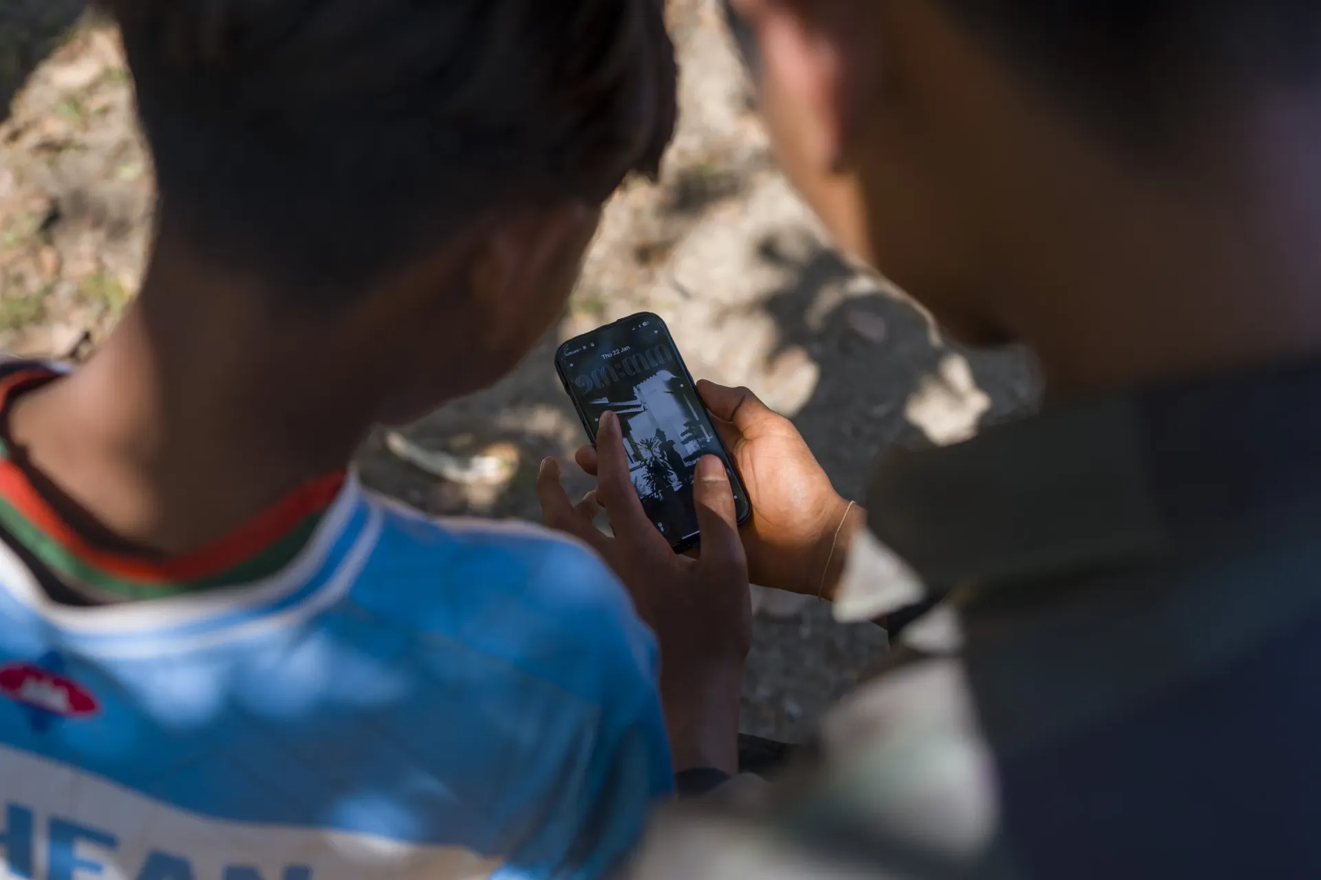 Dos ni&ntilde;os  mirando la pantalla de un tel&eacute;fono m&oacute;vil