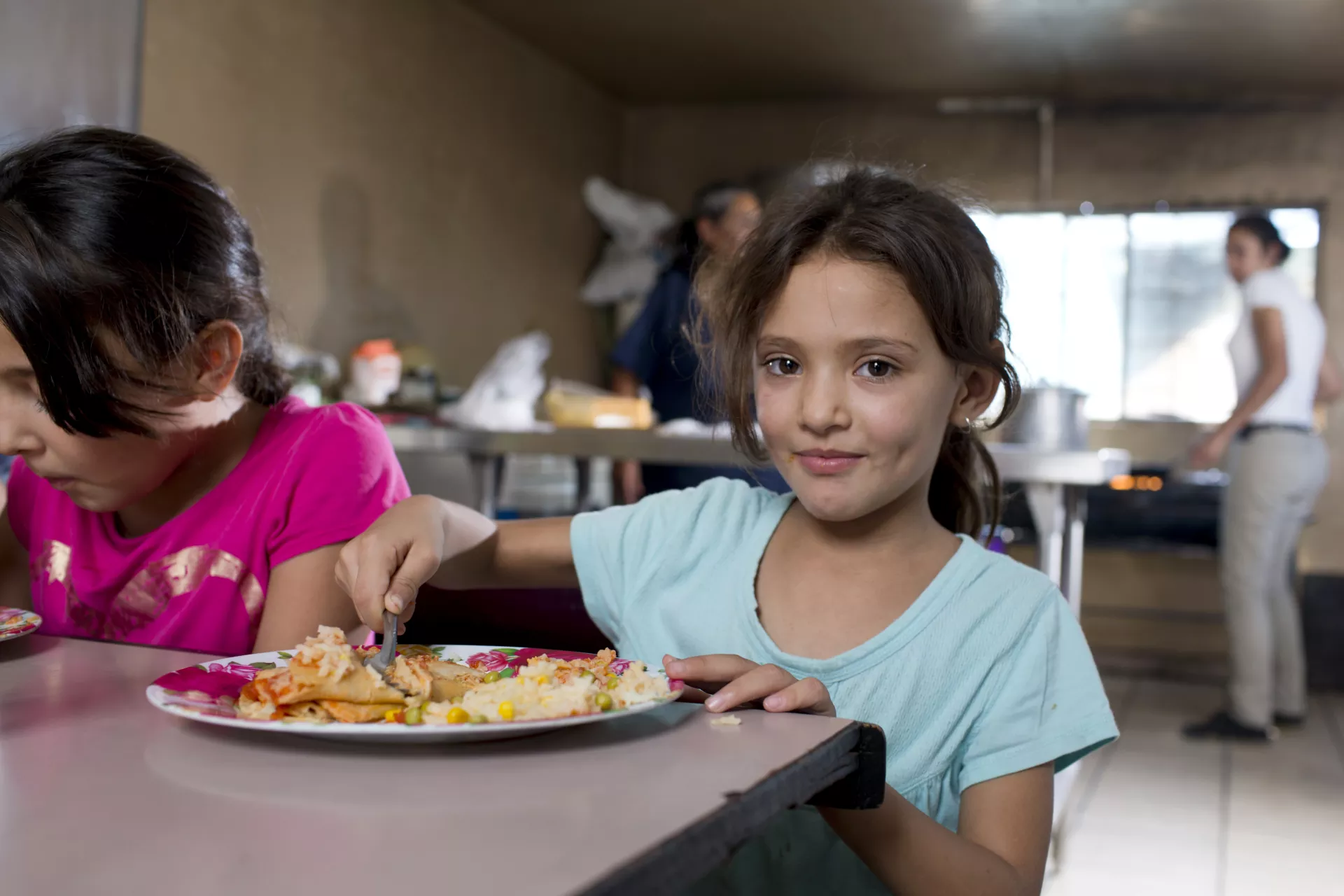 : Una ni&ntilde;a disfruta una comida nutritiva en un comedor, ejemplo de alimentaci&oacute;n saludable para ni&ntilde;os.