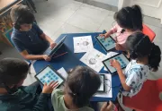 Estudiantes sentados alrededor de una mesa utilizando equipos electr&oacute;nicos en el aula como parte del programa Akelius.