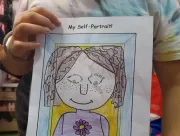 A student shows the self portraid she made as part of the English lesson