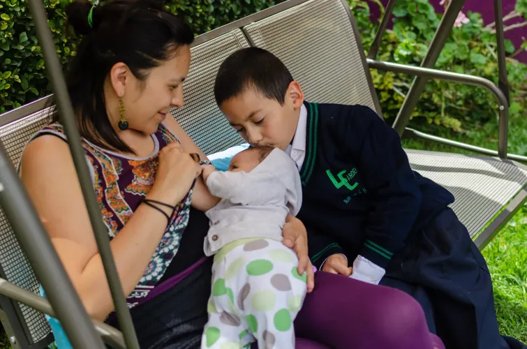 Una familia de mam&aacute;, beb&eacute; e hijo. La madre est&aacute; dando pecho a su beb&eacute;