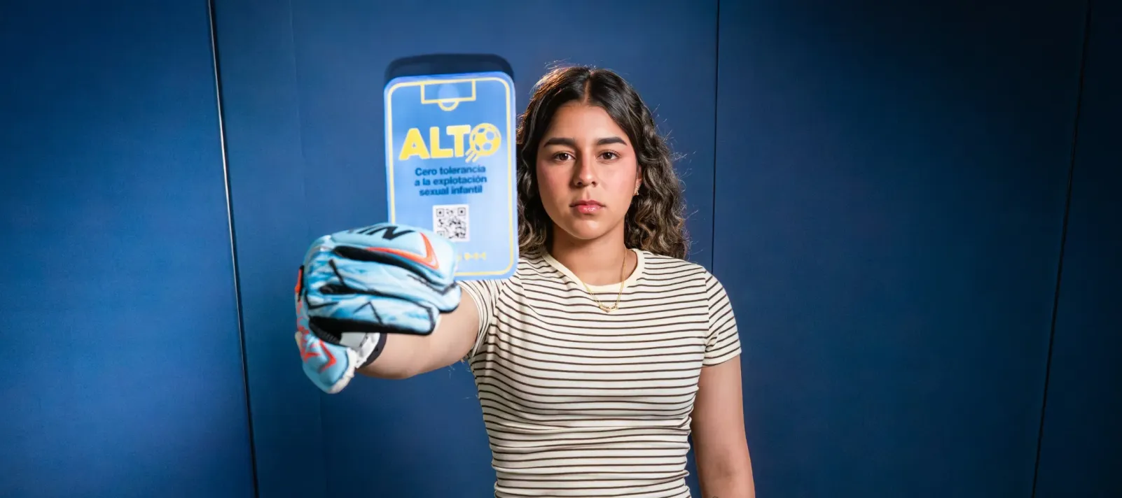 Futbolista con guantes de portero sosteniendo la Tarjeta Azul de Cero Tolerancia contra la explotaci&oacute;n sexual infantil en M&eacute;xico