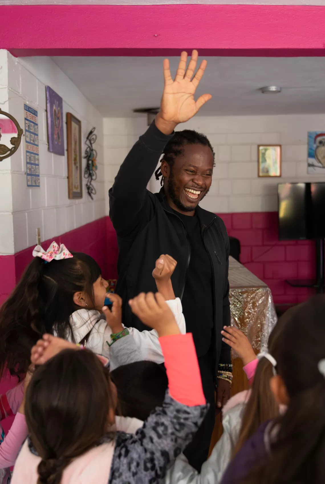 Ishmael high fives children at a community center in Tijuana