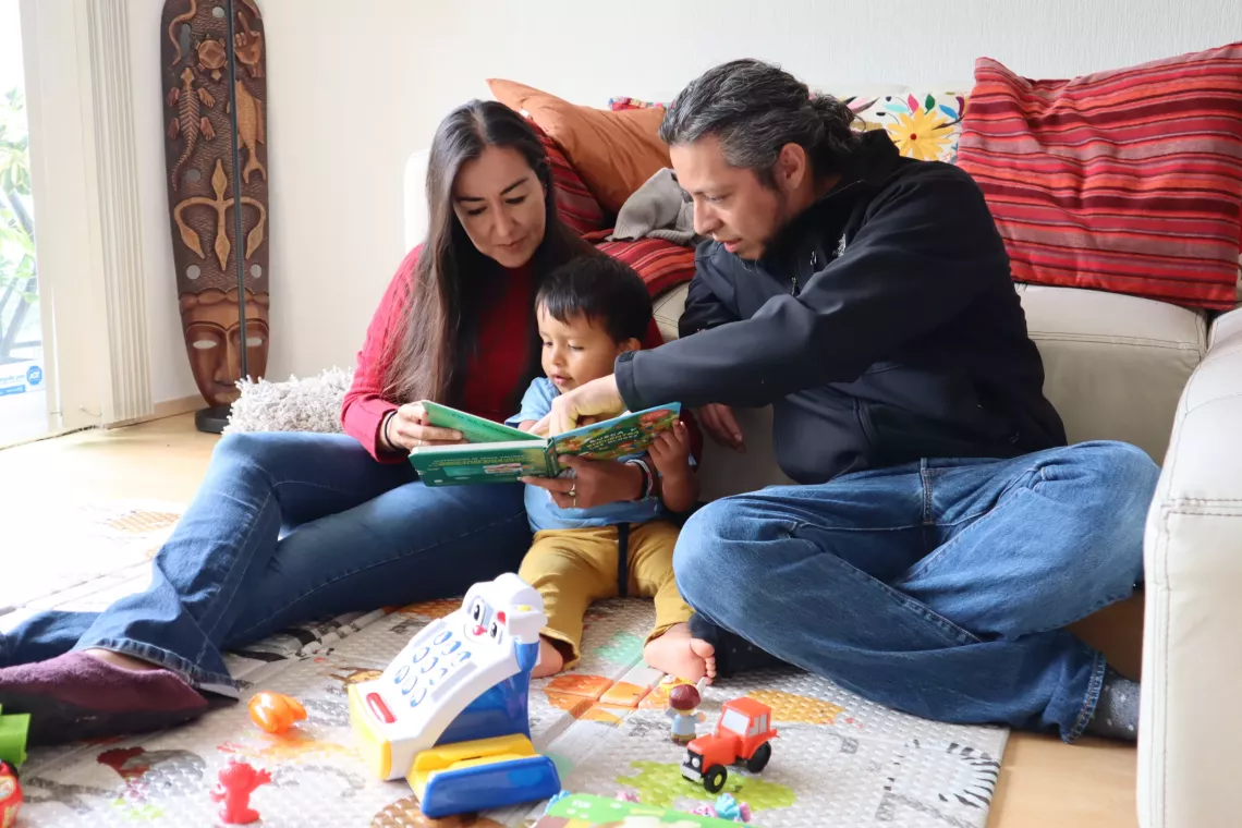 Pap&aacute; y mam&aacute; leyendo con su hijo peque&ntilde;o