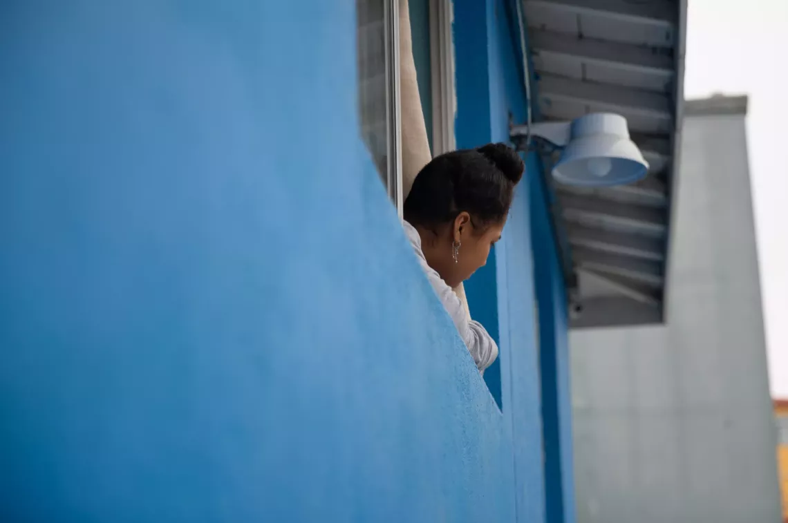 una adolescente asomada por la ventana