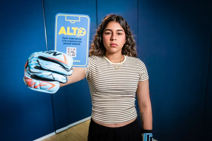 Futbolista sostiene la tarjeta azul de la campa&ntilde;a cero tolerancia contra la explotaci&oacute;n sexual