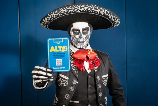 El Charro Gonz&aacute;lez con traje de mariachi y maquillaje de catrina sosteniendo la Tarjeta Azul ALTO, apoyando la campa&ntilde;a Cero Tolerancia contra la explotaci&oacute;n sexual infantil en M&eacute;xico