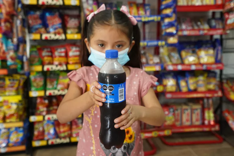 Ni&ntilde;a sosteniendo una bebida con etiquetado