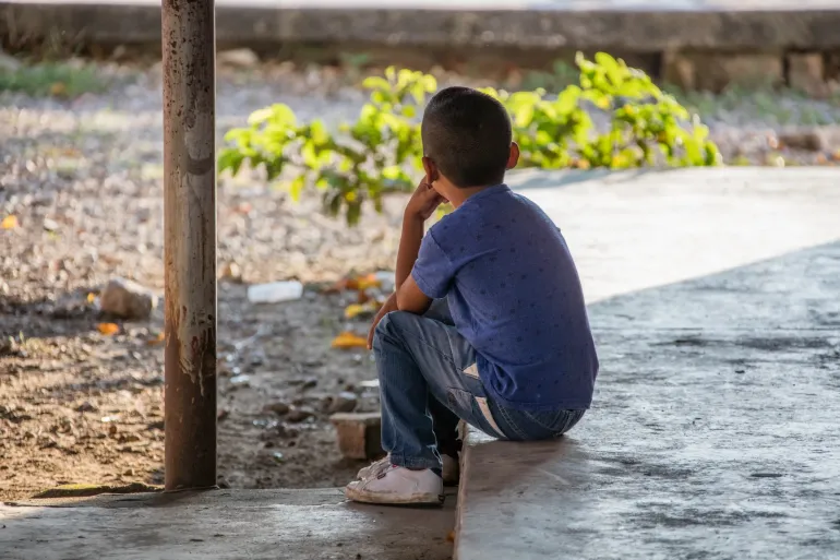 Ni&ntilde;o sentado en un patio