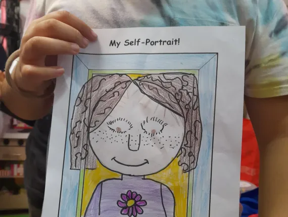 A student shows the self portraid she made as part of the English lesson