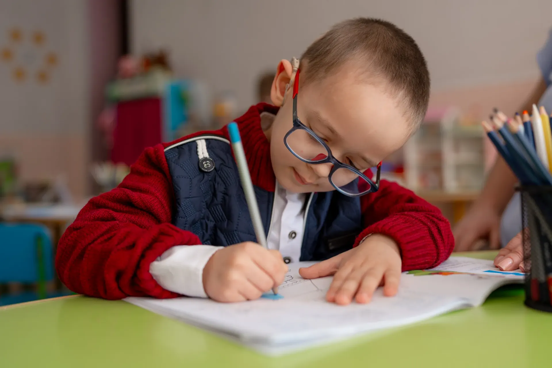 Damian, &icirc;n v&acirc;rstă de 5 ani, la grădiniță, rezolvă o fișă educativă.
