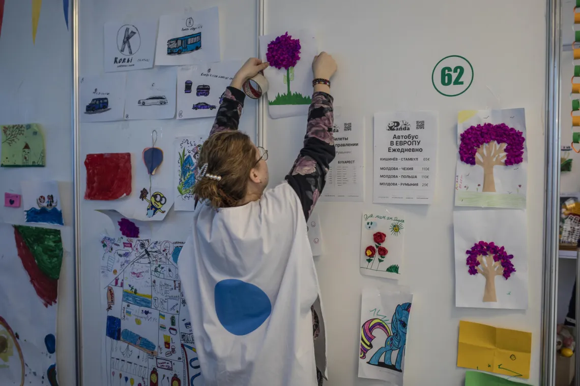 A Blue Dot worker hangs up colourful artworks from Ukrainian refugees.