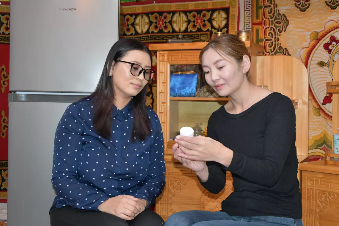 A doctor is visiting Munkhtuya at her home and explaining a multiple micronutrient supplement's benefit.