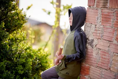A boy with a hood and a baseball bat