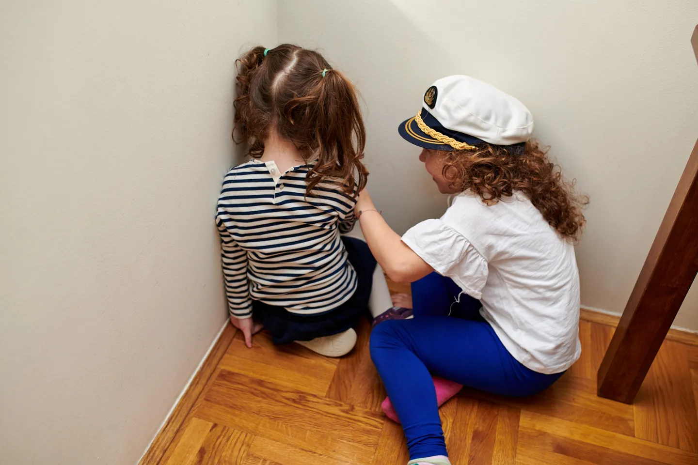 Two girls sitting in the corner turned back