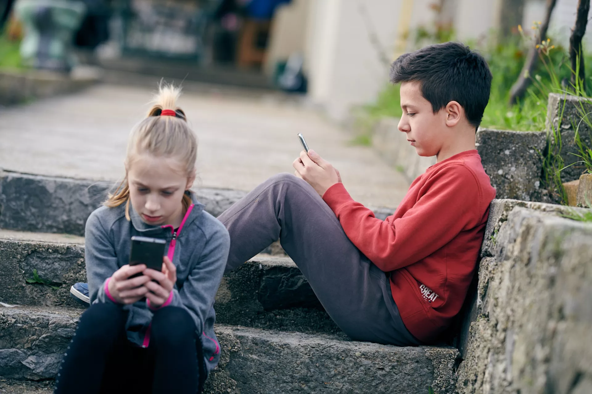 dvoje djece koriste mobilne telefone