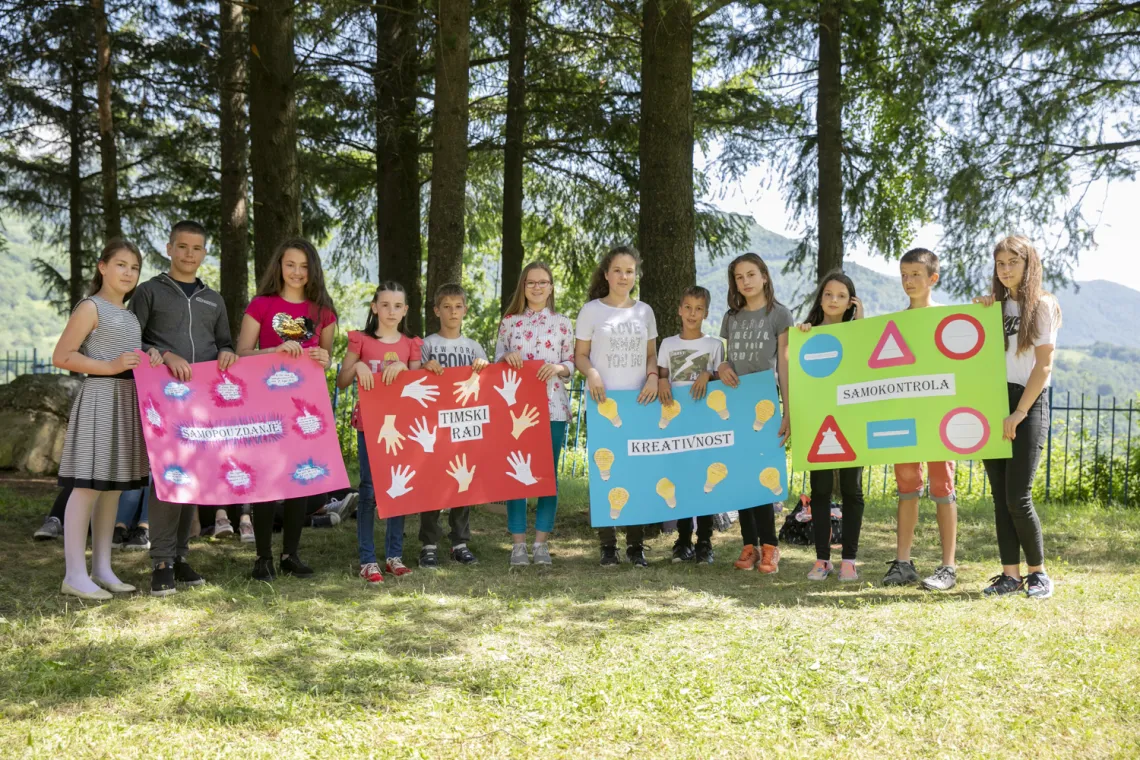 Children holding a poster with social and emotional skills