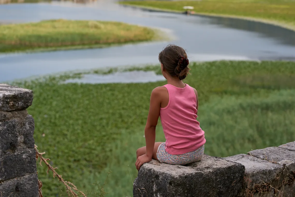 A girl sitting on the wall with her back turned to camera