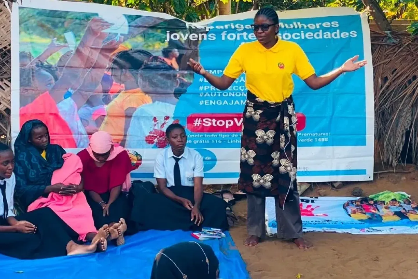 Aniceta Januario S&aacute;bado, 27, an ASCHA peer educator and mentor, addresses a mixed-generation audience in Horta-C on July 29. Banners promoting girls' empowerment and education hang behind her. 