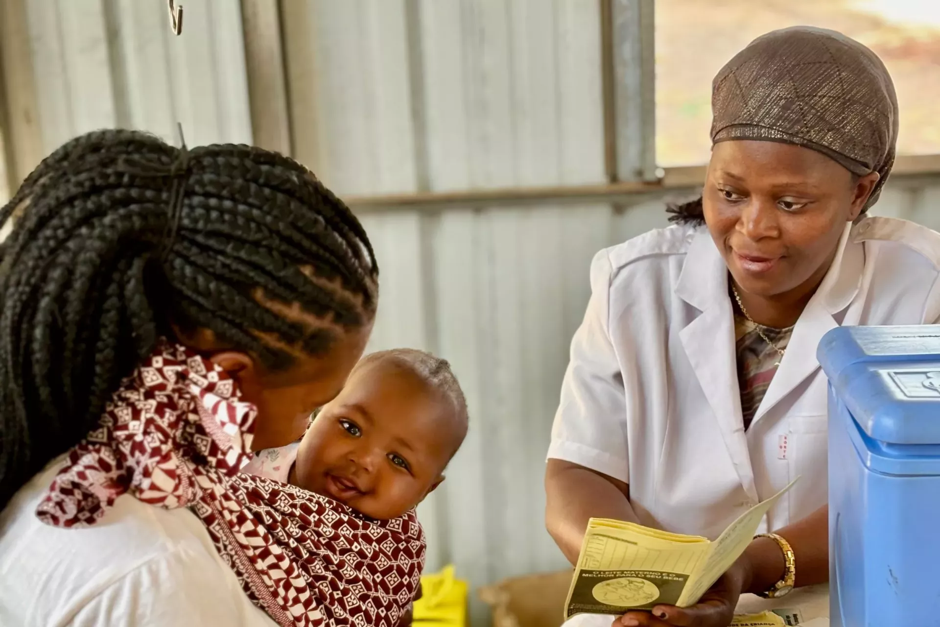 Uma t&eacute;cnica de sa&uacute;de conversando com uma m&atilde;e com uma beb&eacute; ao colo durante uma consulta m&eacute;dica numa comunidade remota de Mo&ccedil;ambique.
