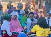ASCHA peer educators, in yellow polo shirts, lead a small-group discussion during the dialogue in Horta-C. A performer with white face paint, still in character from the play, takes part in the conversation.