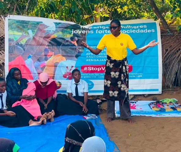 Aniceta Januario S&aacute;bado, 27, an ASCHA peer educator and mentor, addresses a mixed-generation audience in Horta-C on July 29. Banners promoting girls' empowerment and education hang behind her. 