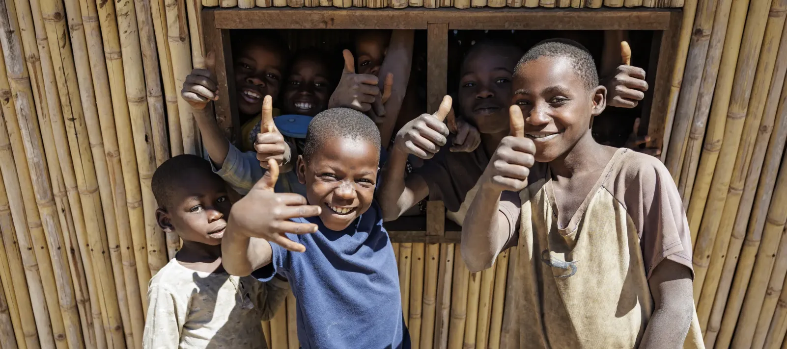 A group of smiling children giving the thumbs up