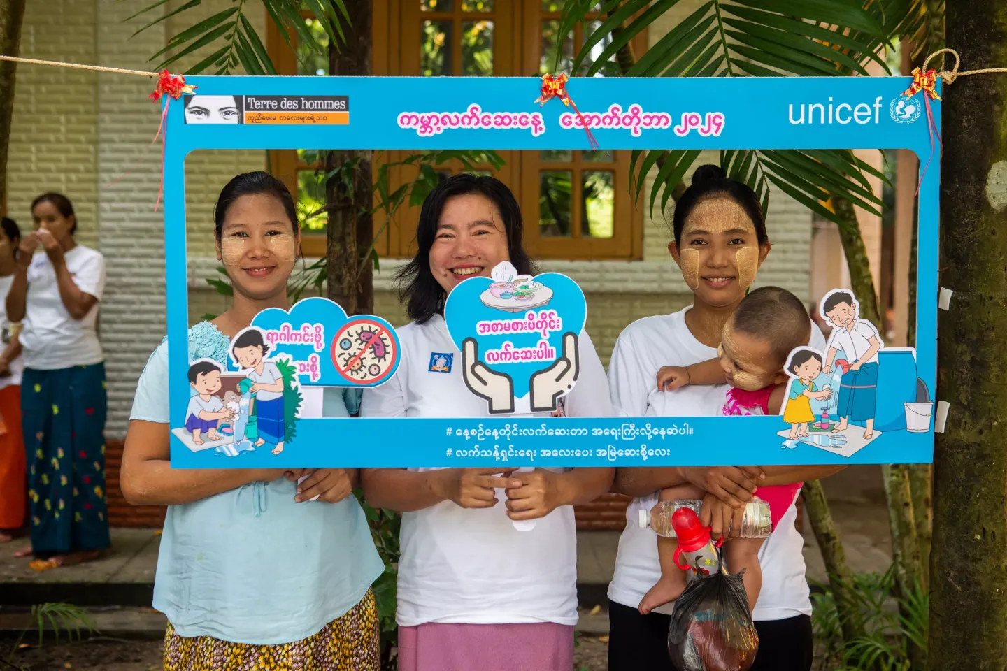 A group of mothers posting with handwashing signs. 