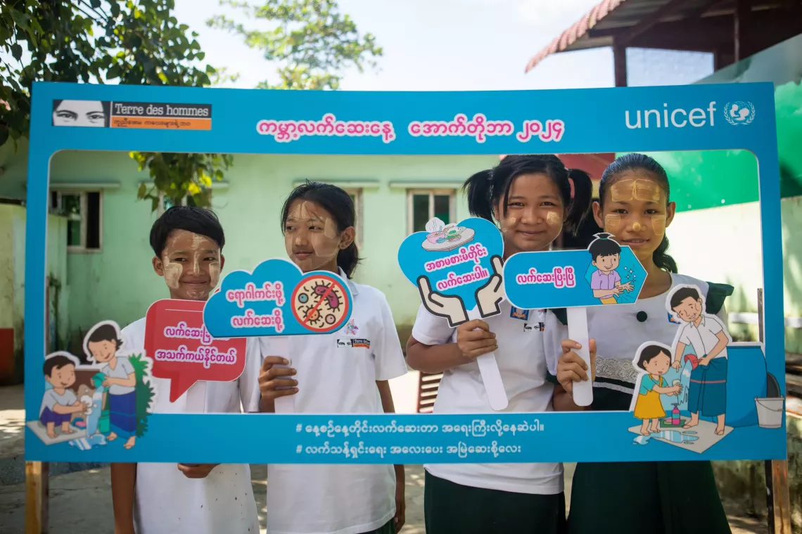 A group of girls posting with handwashing signs. 