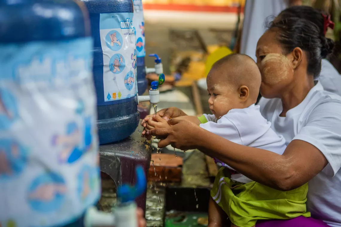 A mother helpings her son to wash his hand. 