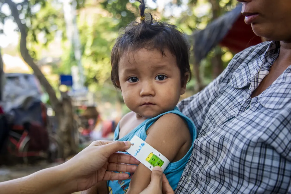 A health worker measures a child&rsquo;s arm with a MUAC tape during a nutrition check.