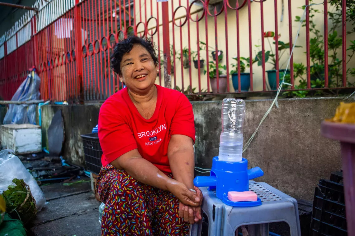 A woman washing her hand using UNICEF tippy tap. 