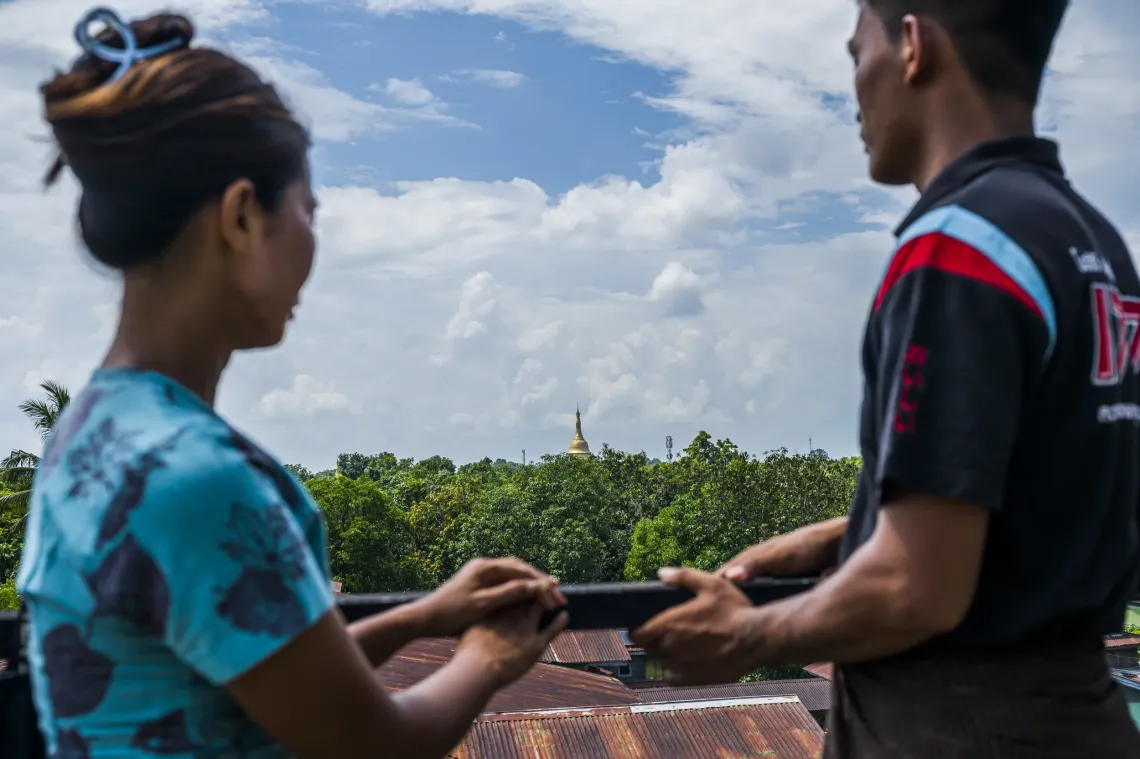 Photo of a mother and her son looking beyond the sky. There is a pagoda in the background. 