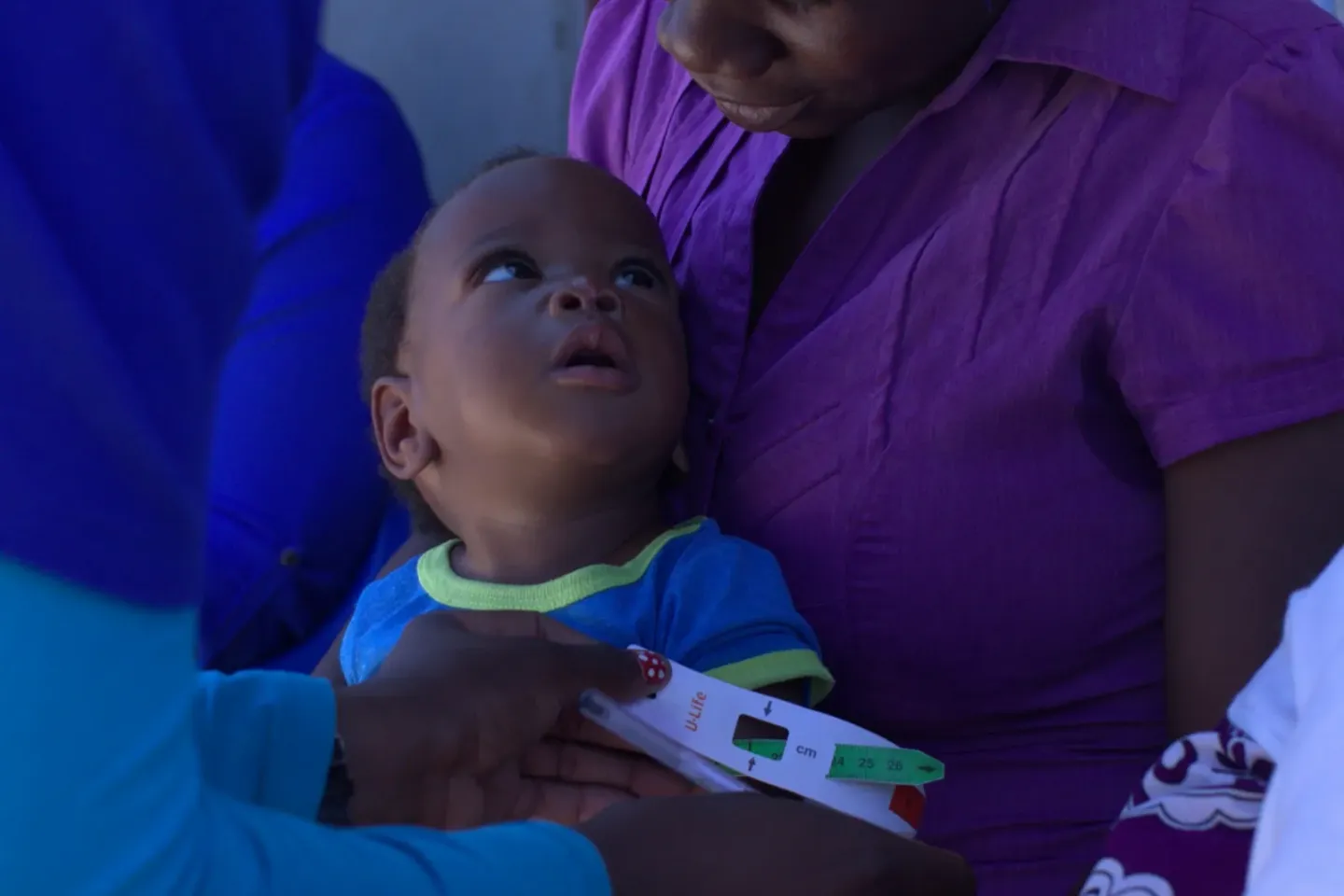 baby boy being measured for nutritional status with mid-upper arm circumference (MUAC) measuring tape