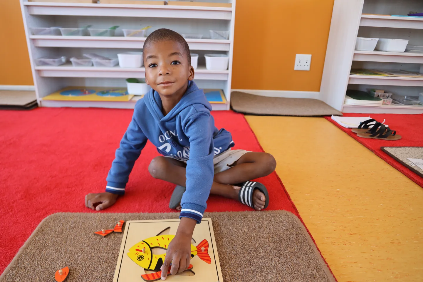 young boy sitting on carpet building a puzzle