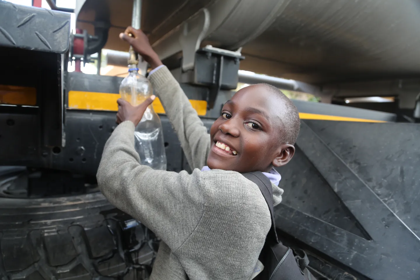 young girl getting safe drinking water from a water truck
