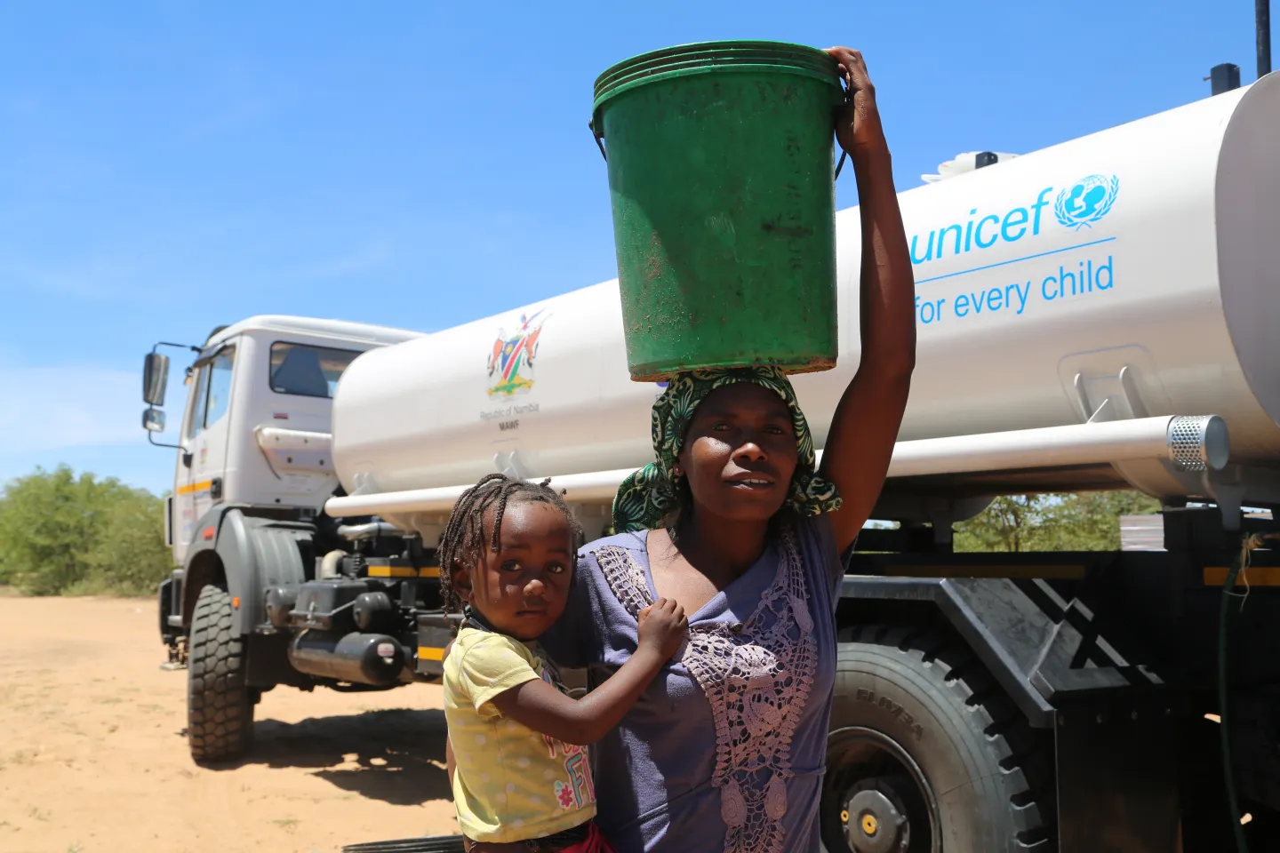 Mother carrying her daughter and a bucket of safe drinking water 