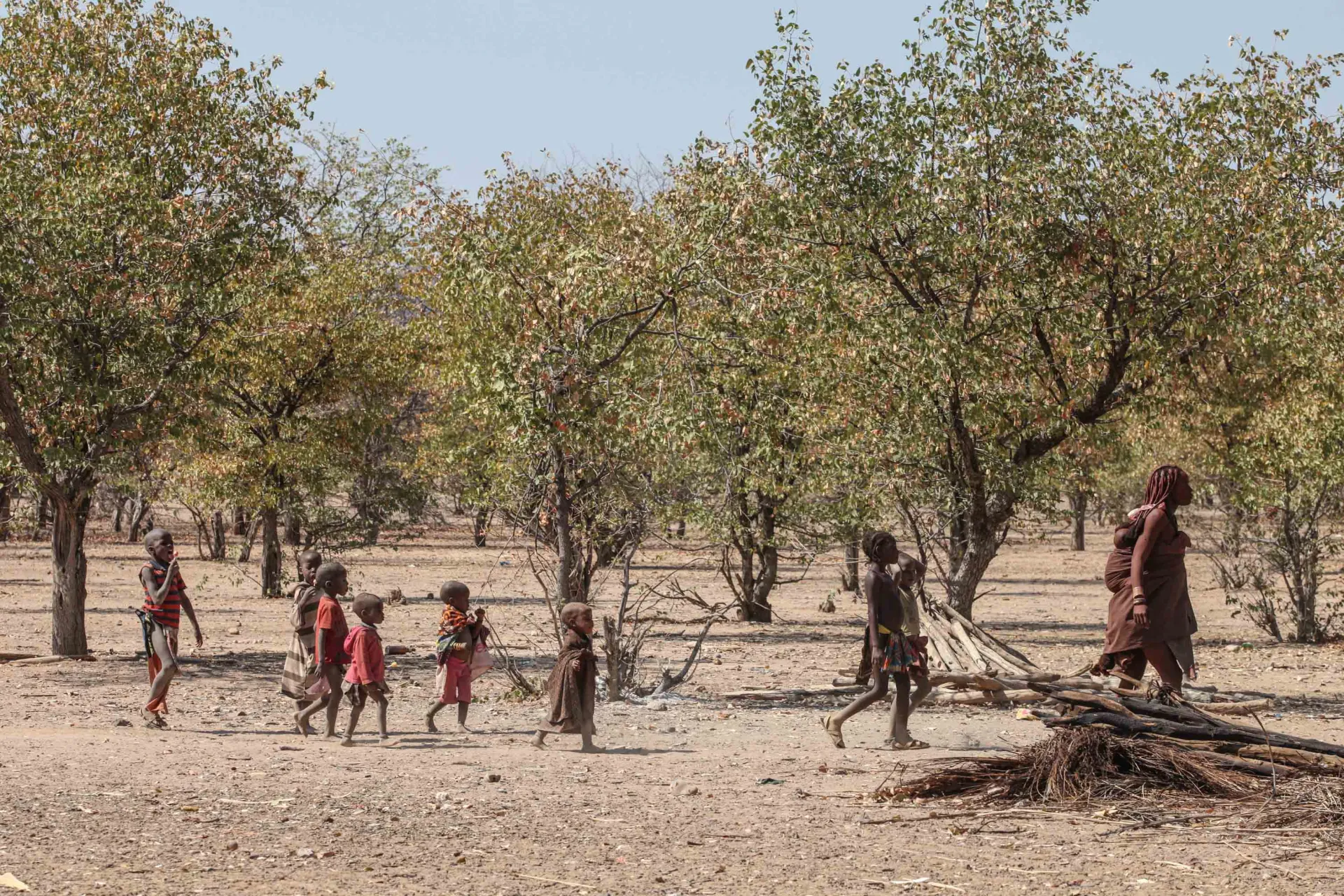 young children walking behind woman in village