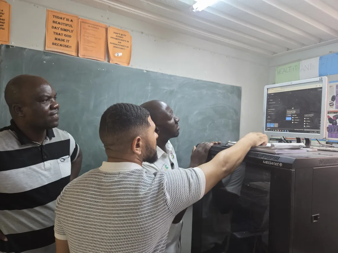 Three technicians from Ministry of Education, MICT and GIGA discuss mapping of the giga meter